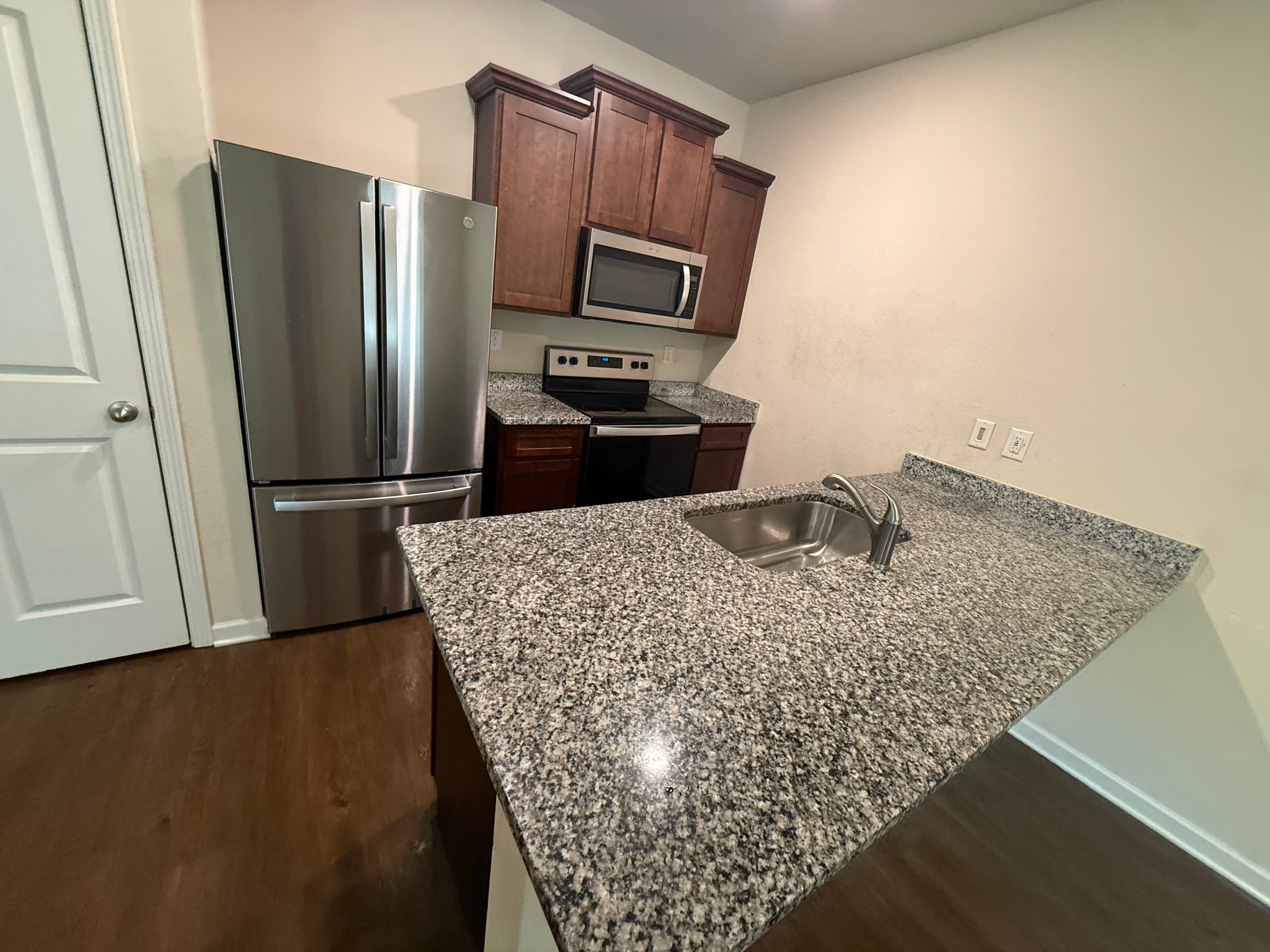 Modern kitchen with stainless steel appliances, dark wood cabinets, and a speckled granite kitchen island.